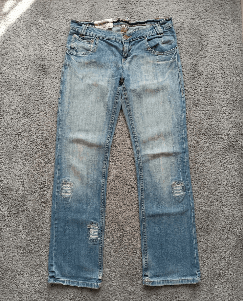 Jean bleu washed avec déchirures aux genoux, vue dos sur tapis gris